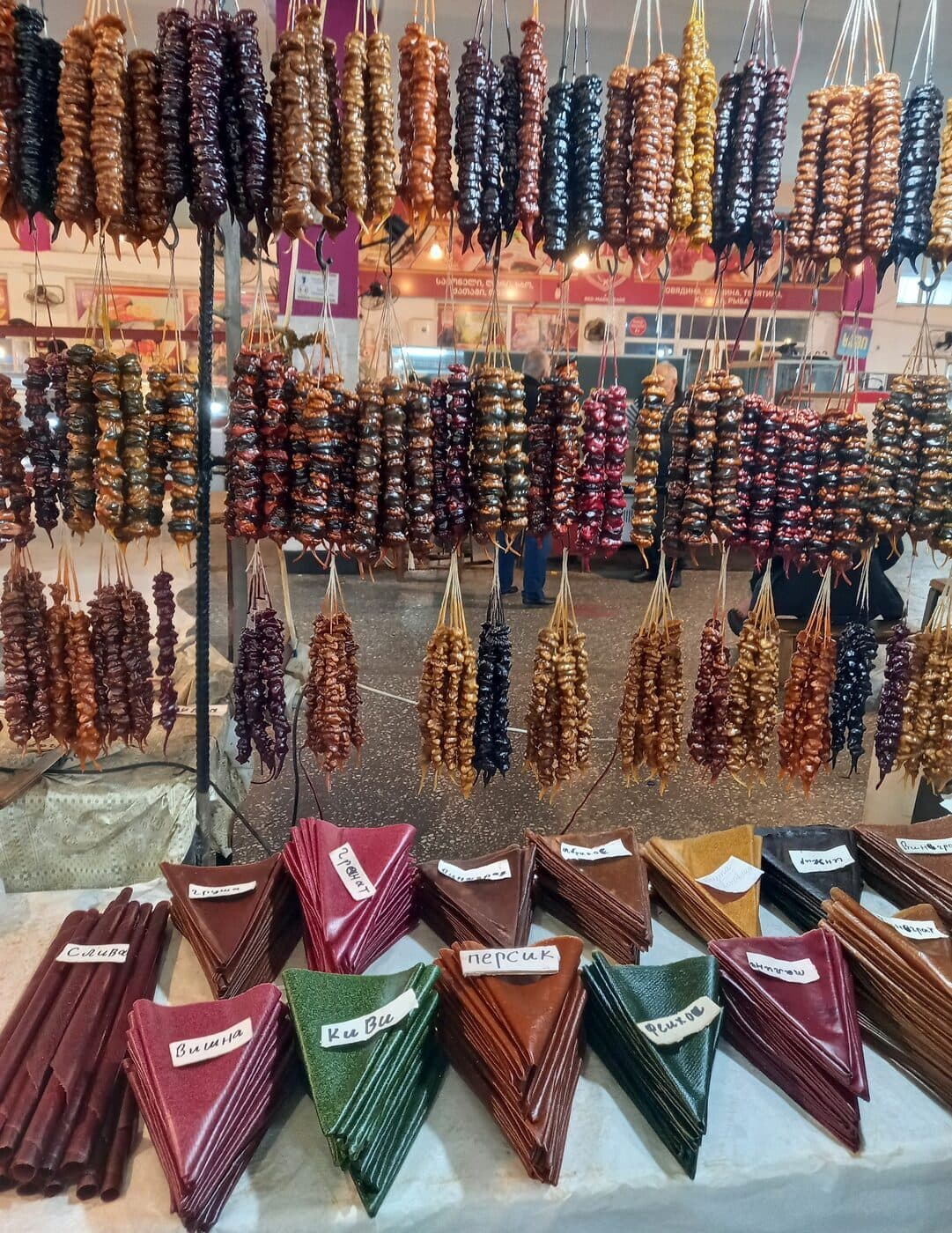 Colorful churchkhela, Georgian grape-and-walnut candy, hanging at a market stall